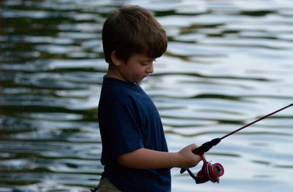 Child with fishing rod engaged completely in waiting for that first strike